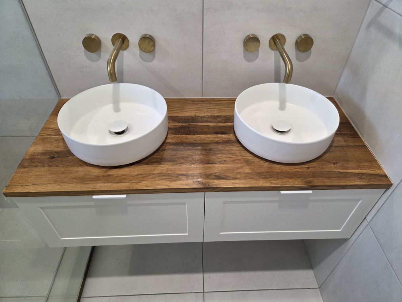 Timber-top double vanity with two round basins and brass taps