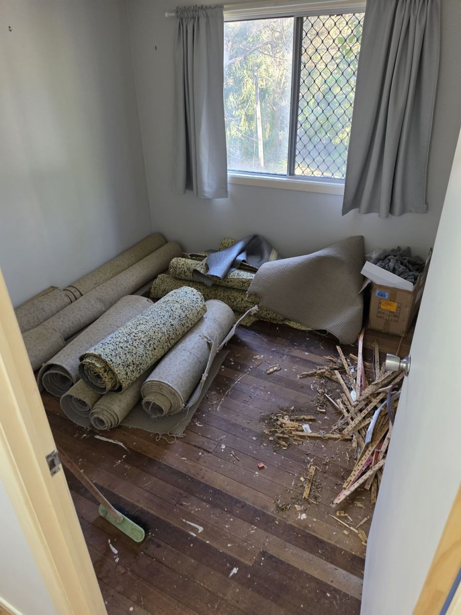 Bedroom with old carpet rolled up and underlay being lifted