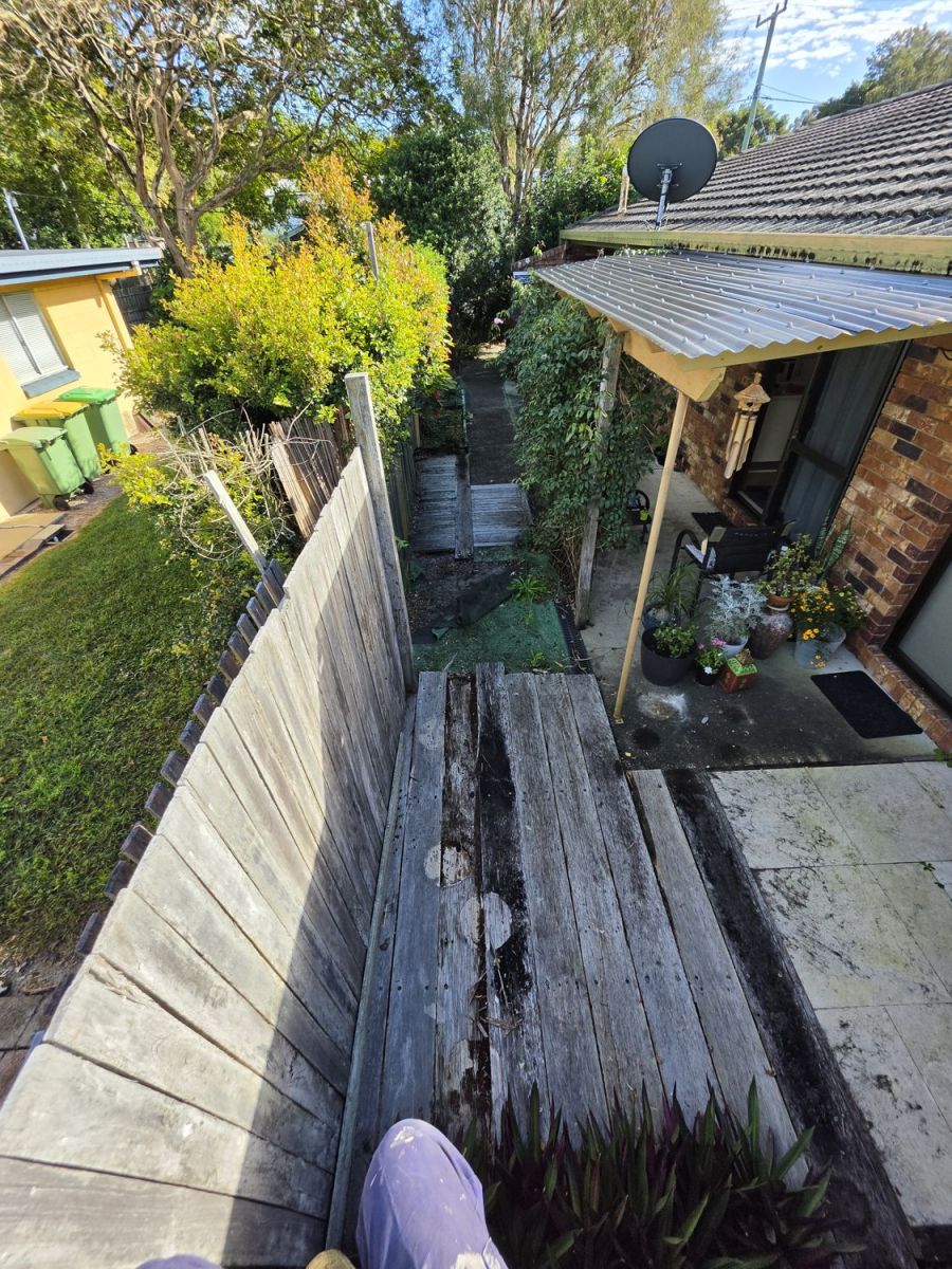 Side of a house with old rotted timber sleepers, seen from above, before the work