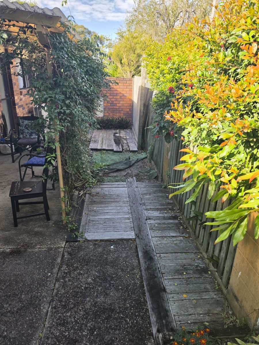 Worn timber sleeper path down the side of a house, before