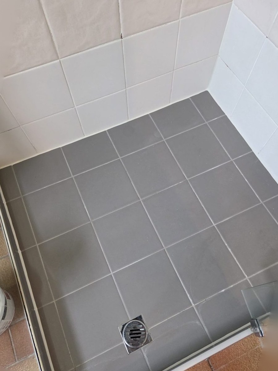 Grey-tiled shower floor re-sealed with fresh silicone